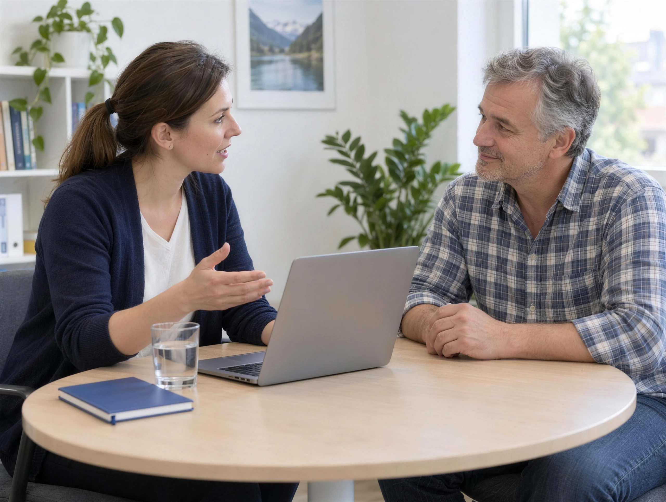 Eine Beraterin bespricht mit einem Arbeitsuchenden am Laptop passende Stellenvorschläge