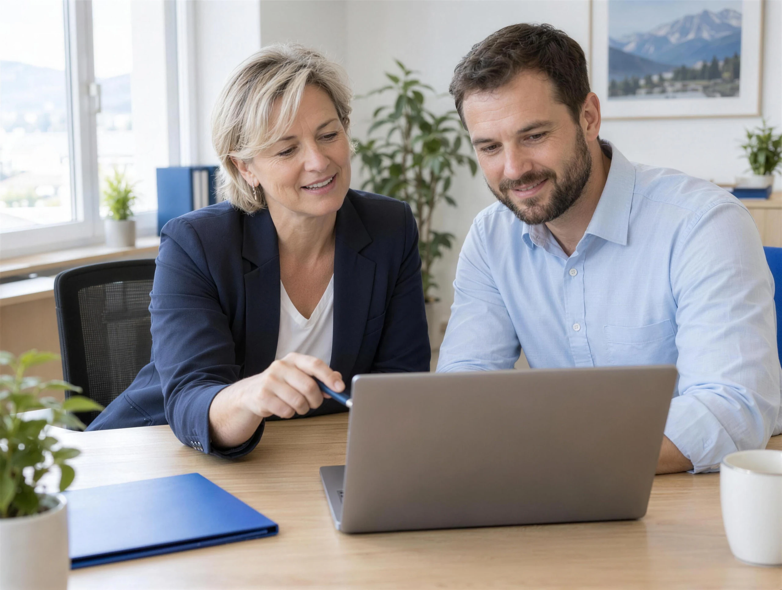 Eine Geschäftsführerin und ein Mitarbeiter besprechen im hellen Büro gemeinsam am Laptop einen Vorschlag der KI